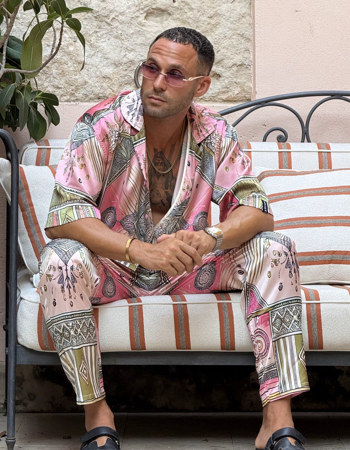 Scar City men's satin co-ord set, seated on a striped sofa, We Hustle